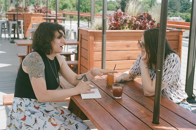 Angel and Avery sitting across from each other at a table, discussing something